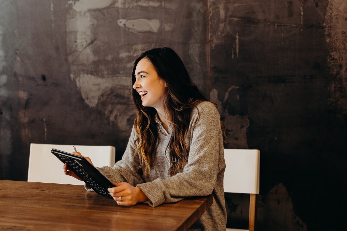 woman sitting around table holding tablet